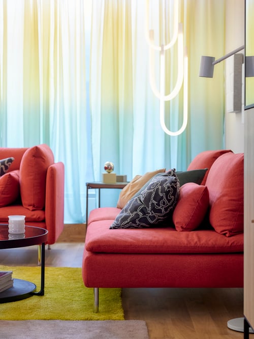 A SÖDERHAMN 3-seat section with a cushion cover on top and a floor lamp behind it, placed in a living room area.