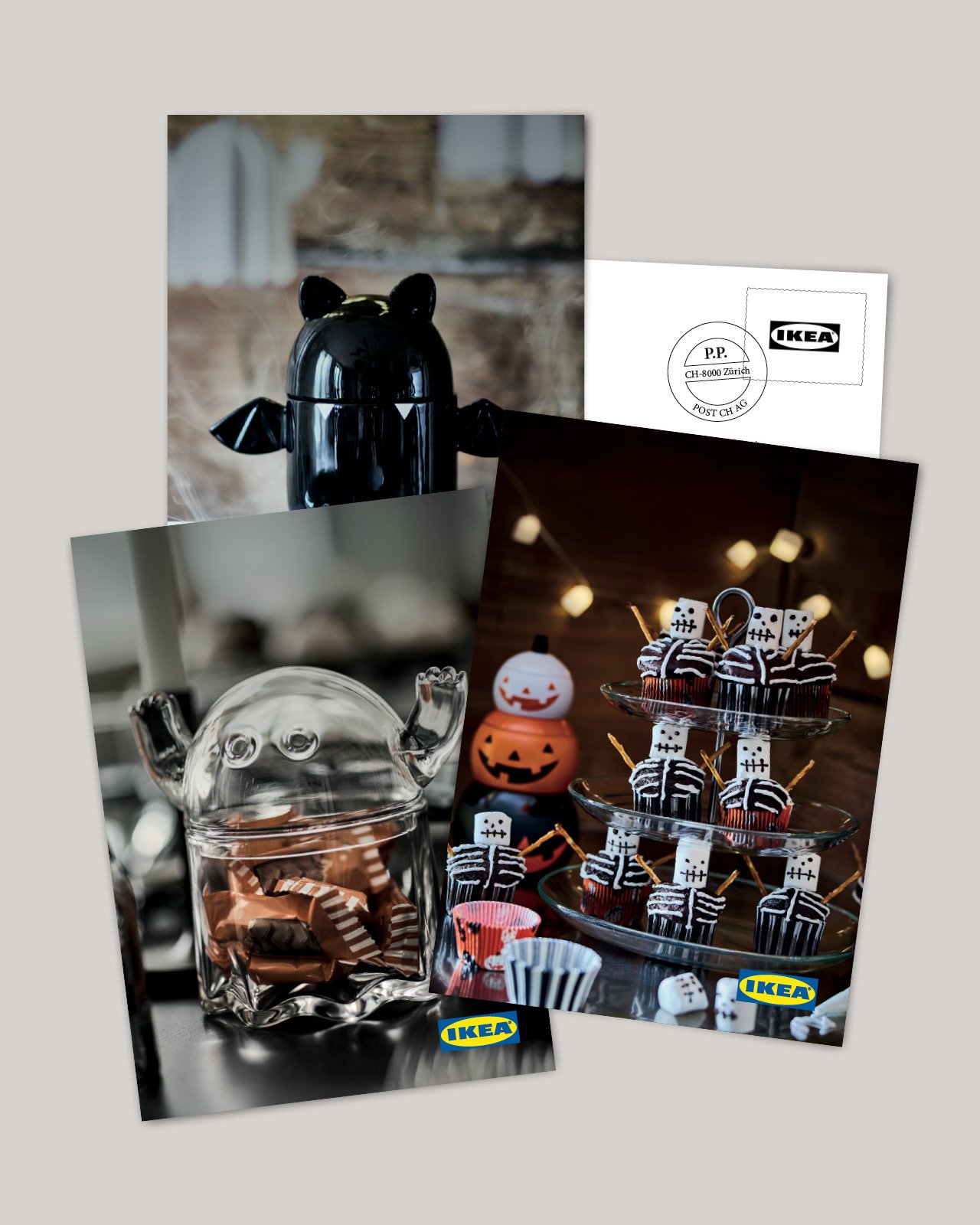 Halloween-Dekoration mit schwarzen und gläsernen Behältern sowie gruseligen Cupcakes auf einem festlich dekorierten Tisch.