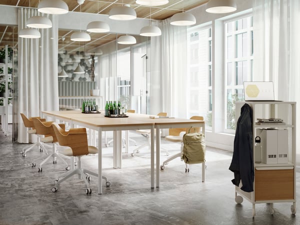 In a white room, a wooden table is surrounded by chairs.
