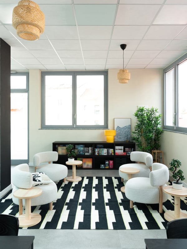 Una zona relax arredata con quattro poltrone, un tappeto STOCKHOLM 2025 e quattro tavolini.