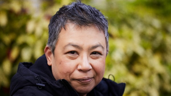 Face portrait of Nancy standing outside with blurred greenery in the background.