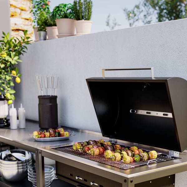 Närbild på en öppen GRILLSKÄR kolgrill i utekök med grillspett liggande på grillgallret. 