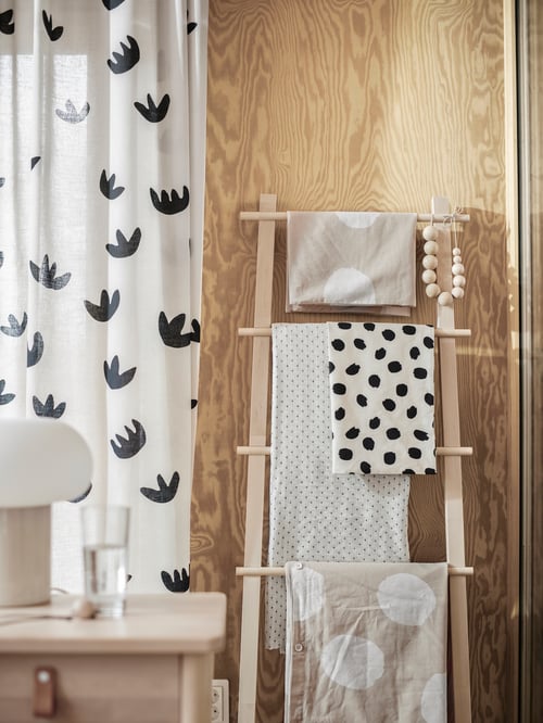 Bedroom with furniture, duvet cover, pillowcases, cushion cover with dotted pattern, bedside table, curtains, glass, lamp.