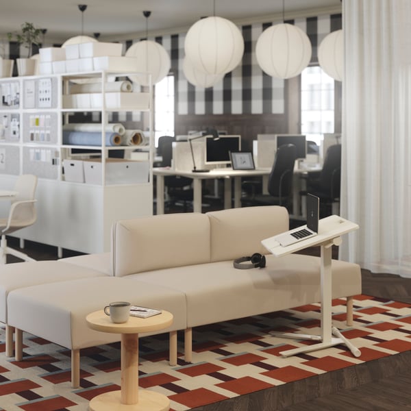 A beige LILLEHEM modular sofa with wooden legs, paired with a white MITTZON laptop table, set on a geometric patterned rug.
