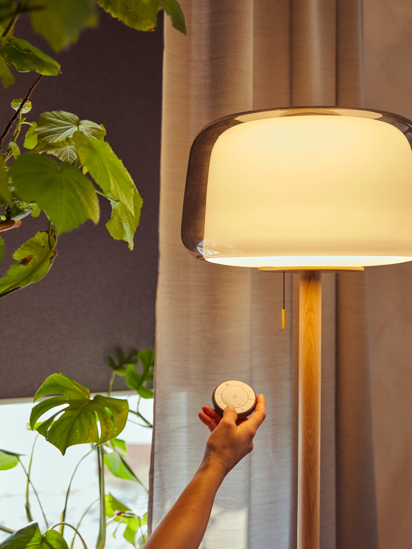 Iemand houdt een IKEA afstandsbediening voor slimme verlichting vast.