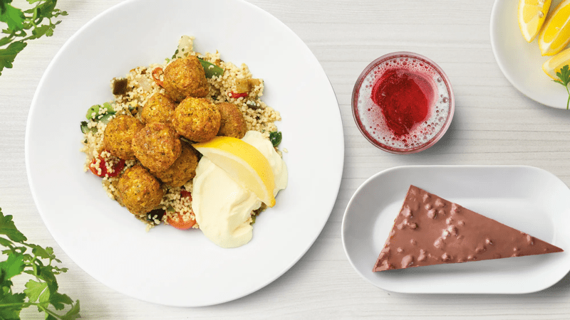 Falafelbullar mit Beilage, einem Stück Daim Torte und einem Schwedenkracherl auf einem Tisch präsentiert