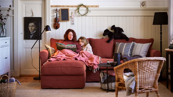 Sofá GRÖNLID en L rojo con una mamá y su hija leyendo un libro de cuentos.