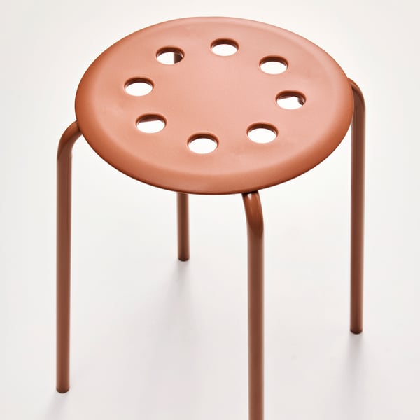 A red-brown MARIUS stool with a circular seat featuring holes, standing on four slender legs against a neutral background.