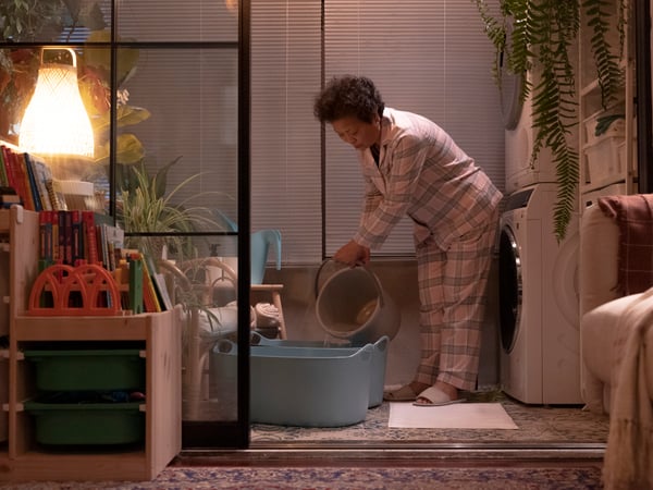 A woman in pyjamas fills up two TORKIS laundry baskets with water.