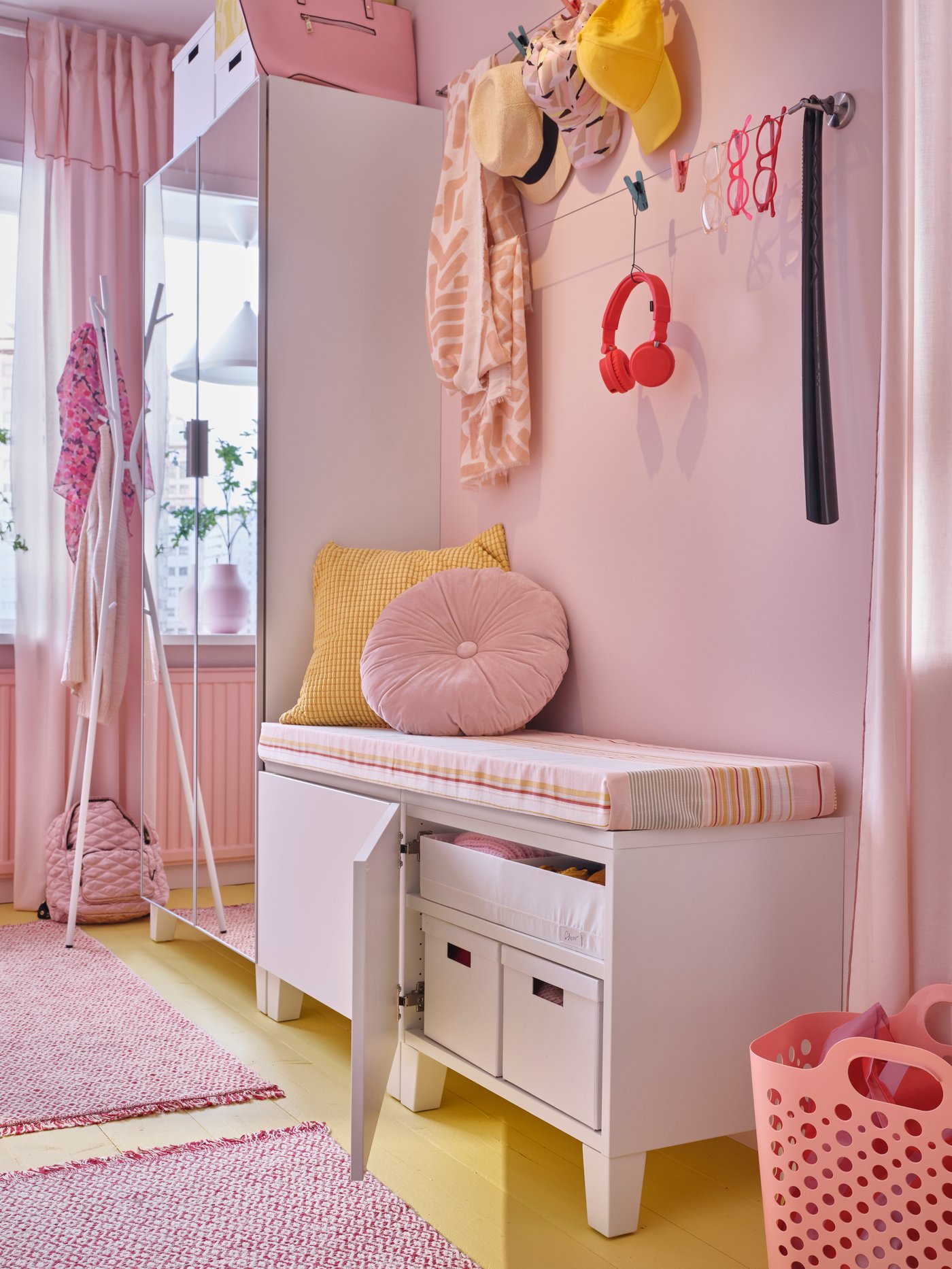 ردهة وردية بها مقعد طويل للتخزين عليه وسادات باللون الوردي والأصفر وباب واحد مفتوح يظهر بداخله صناديق تخزين.