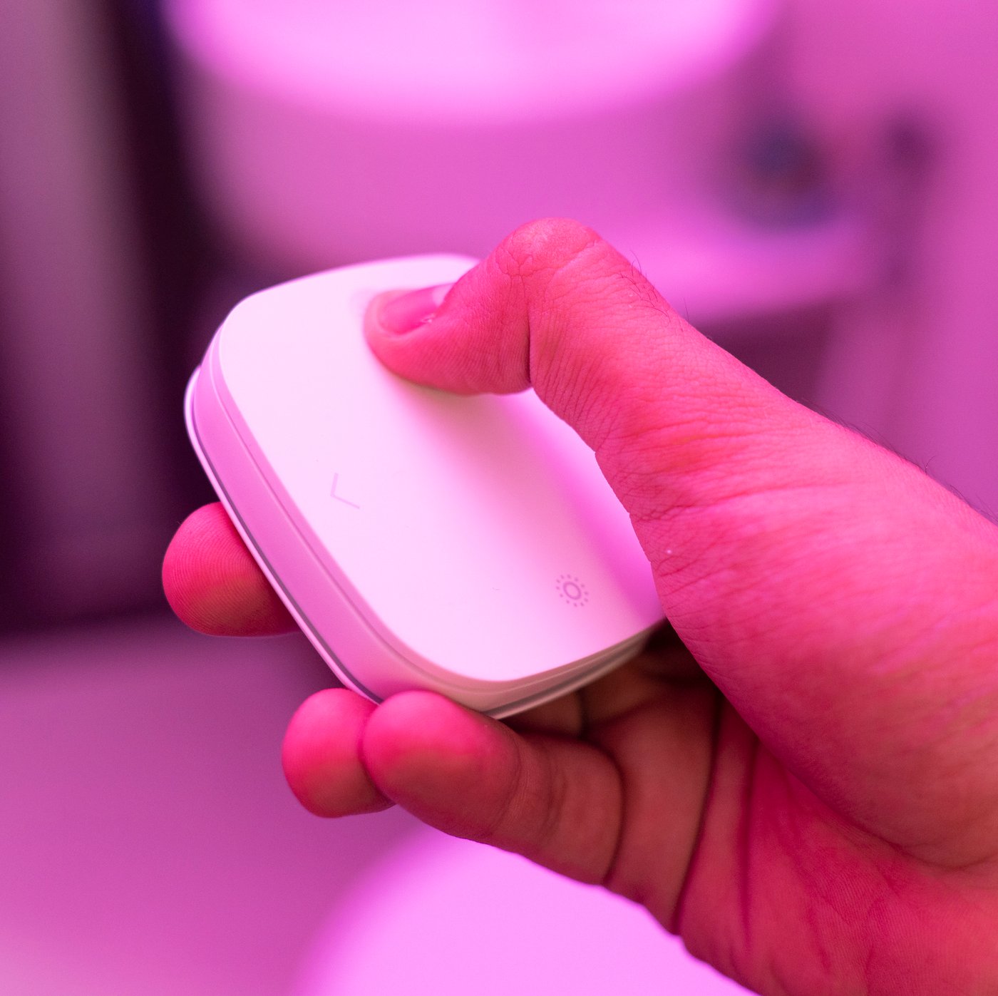 A hand sets the bathroom lights with a STYRBAR remote control.The colour is purple.
