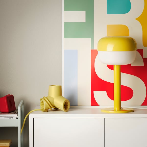A yellow BLÅSVERK table lamp and a yellow HORNFELS extension cord.
