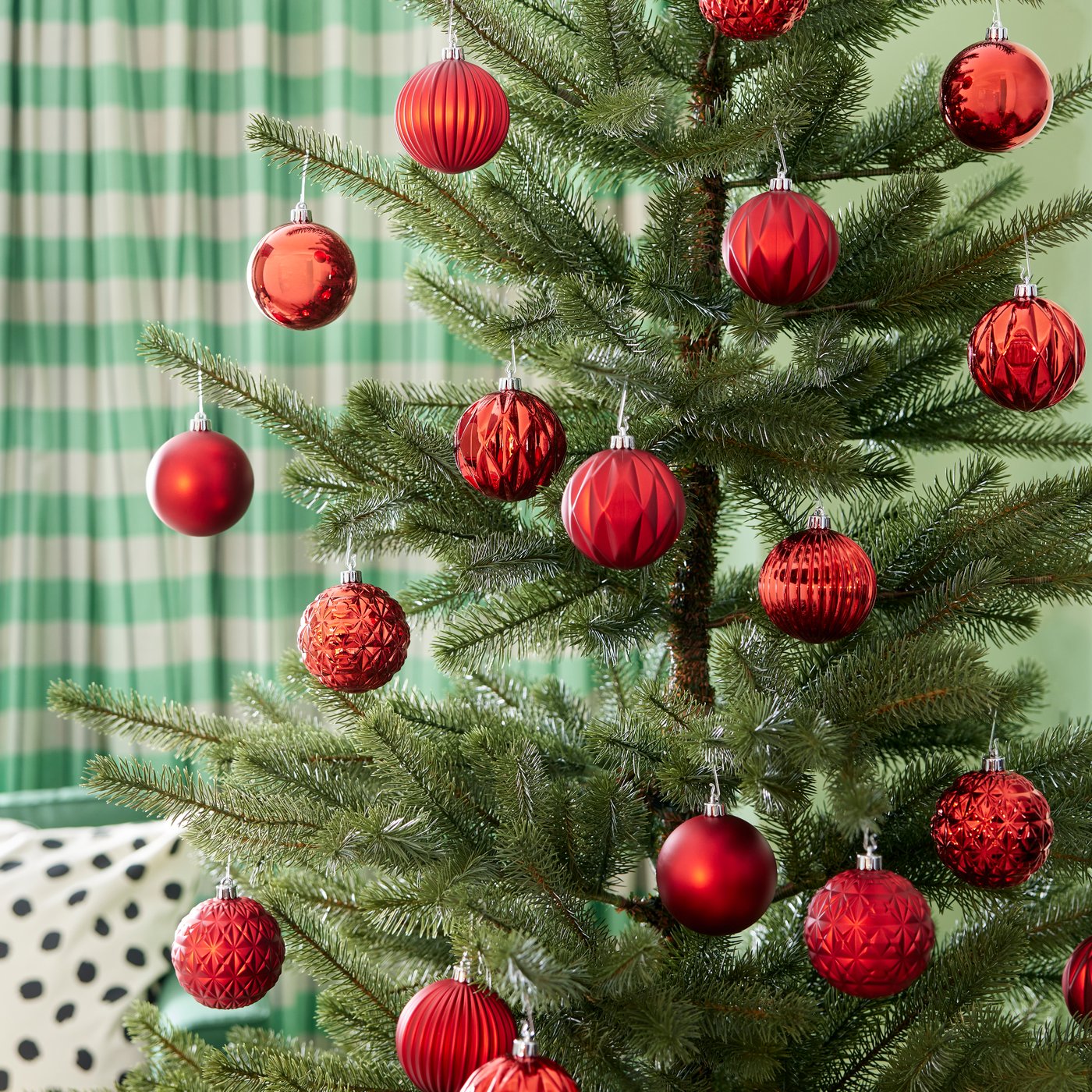 Zoom a un árbol de navidad con adornos de color rojo brillante en sus ramas.