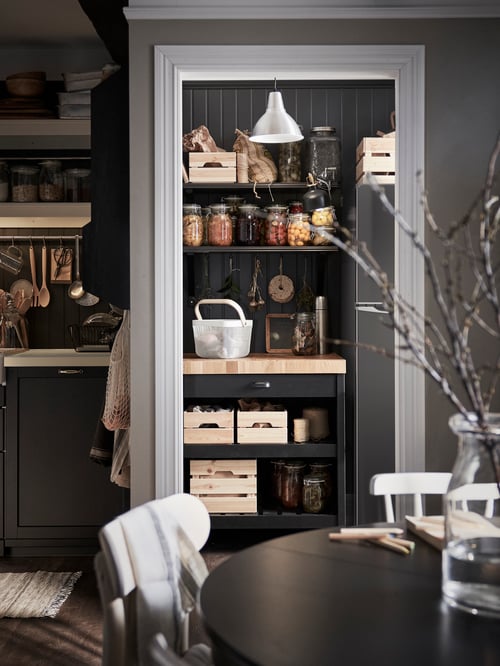 Une cuisine où se trouvent un îlot de cuisine brun en bois et une boîte rectangulaire, à côté d’un réfrigérateur à congélateur supérieur.