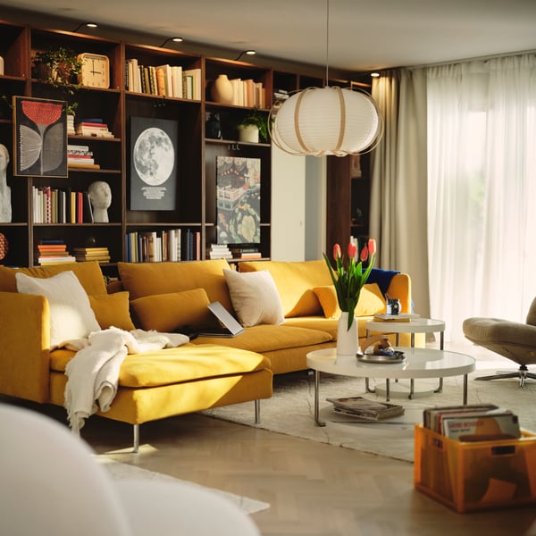A living room with a dark yellow SÖDERHAMN 4-seat sofa-bed and BILLY bookcase with books and decorative items.