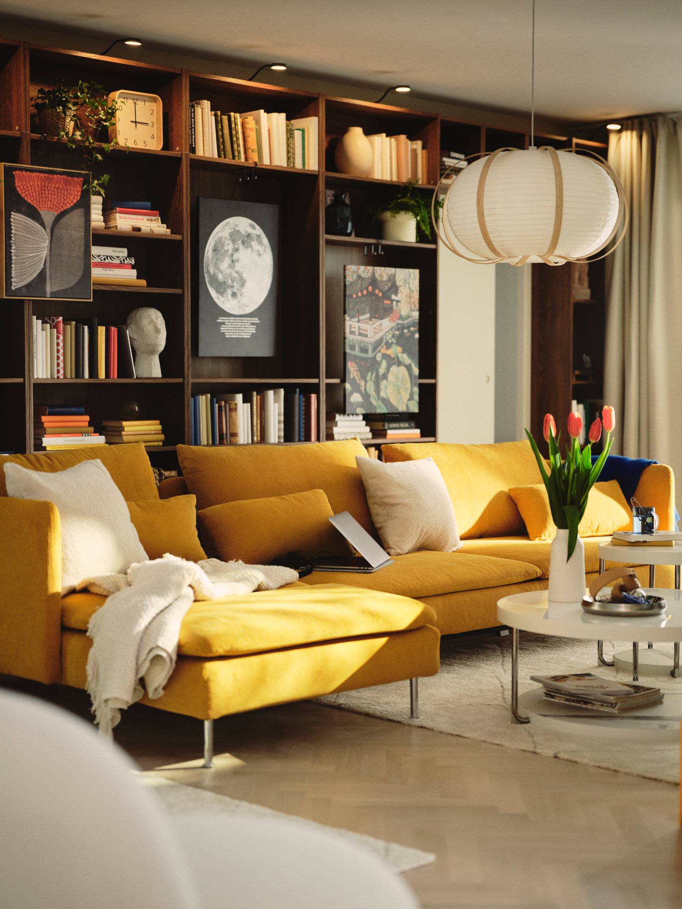 A living room with a dark yellow SÖDERHAMN 4-seat sofa-bed and BILLY bookcase with books and decorative items.