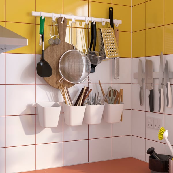 A kitchen wall with SUNNERSTA kitchen rail with four hooks and two containers and KUNGSFORS magnetic knife rack with knives.