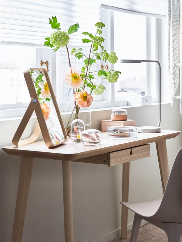 Un escritorio de madera con un espejo de mesa IKORNNES .