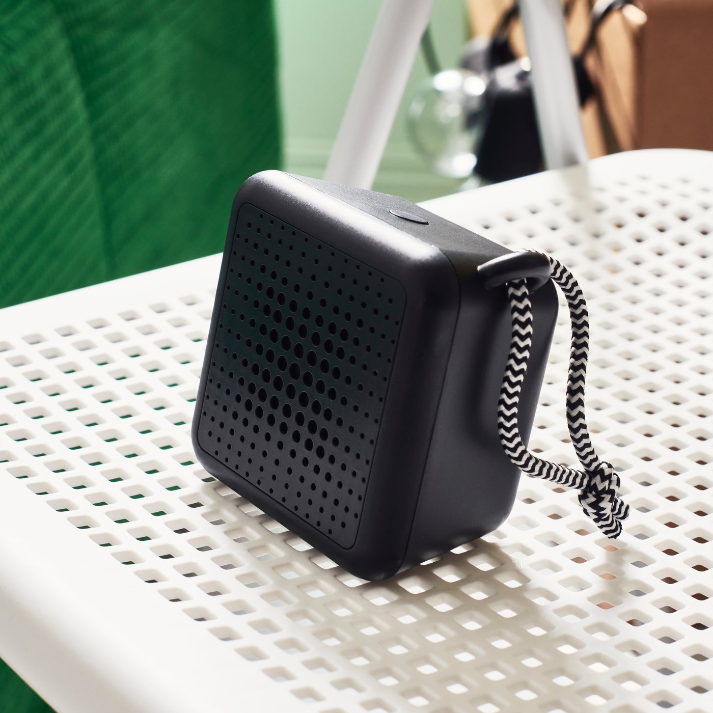 سماعة محمولة سوداء فوق سطح أبيض مثقوب مستوٍ مثقوب.  لها سلك مخطط بالأسود والأبيض. 