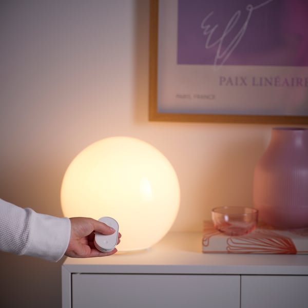 Lit table lamp next to an IKEA RODRET smart control​.