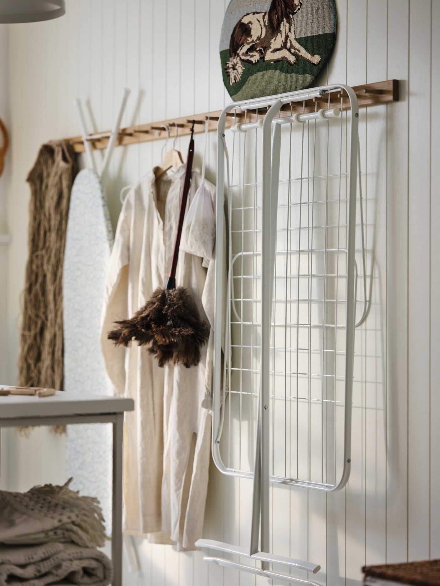 Lavadero con un estante de pared para la ropa y un versátil tendedero plegado de acero con revestimiento en polvo blanco.