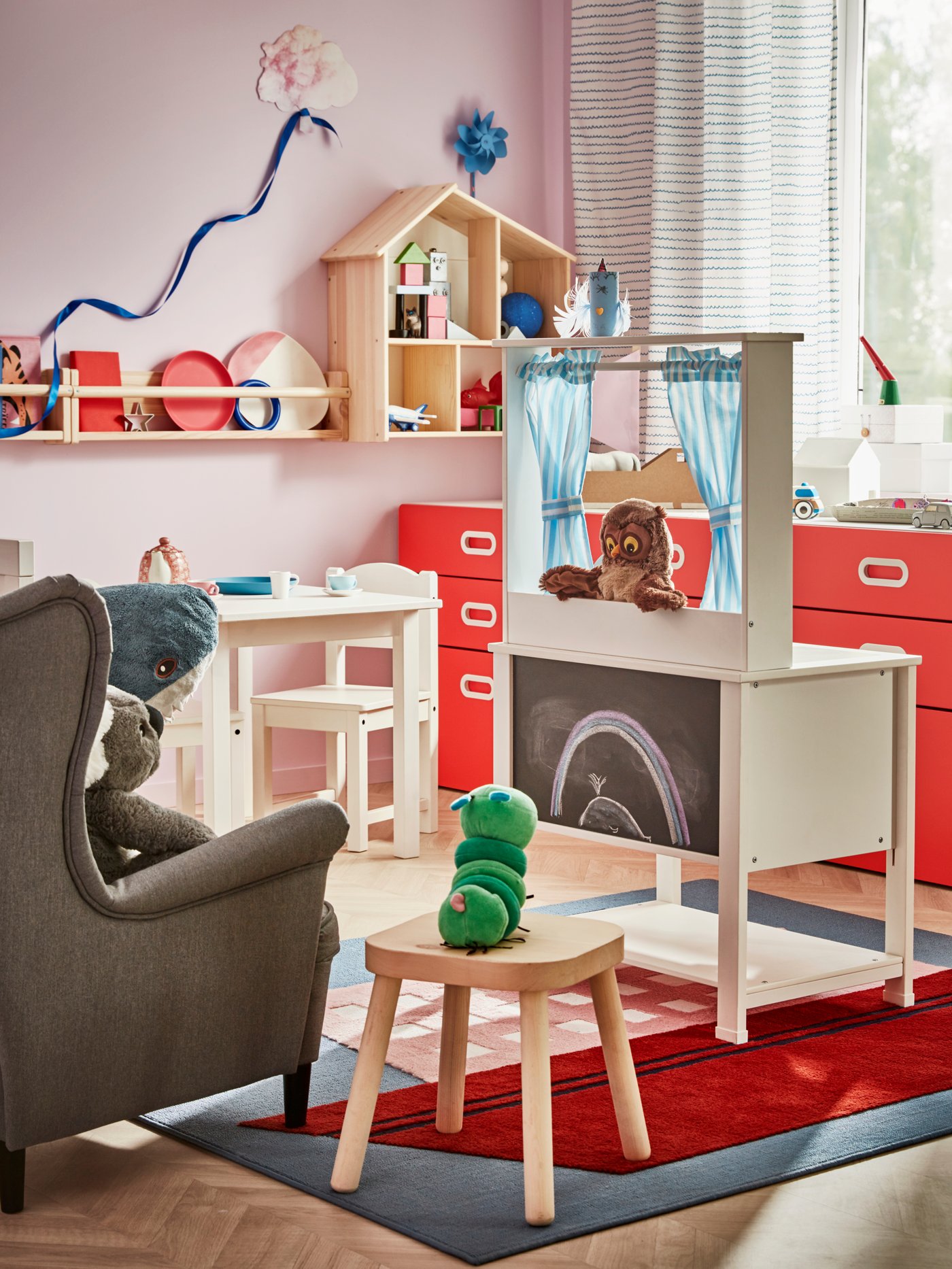 Habitación infantil con un espectáculo de marionetas de búhos en una cocina de juguete SPISIG con cortinas y un público formado por juguetes de peluche sentados en sillas.