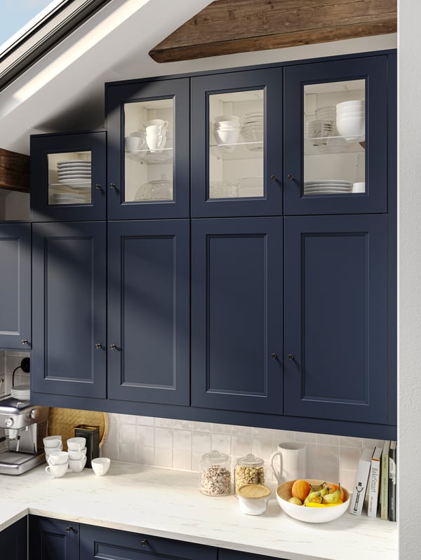 AXSTAD blue shaker wall cabinets with both closed and glass doors, in a bright attic kitchen with white worktop.