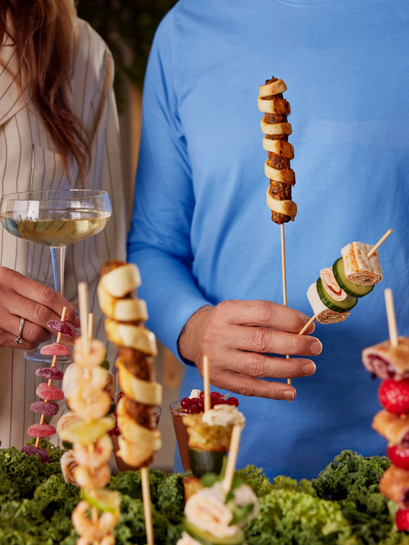 Des personnes qui tiennent des brochettes et un verre à la main