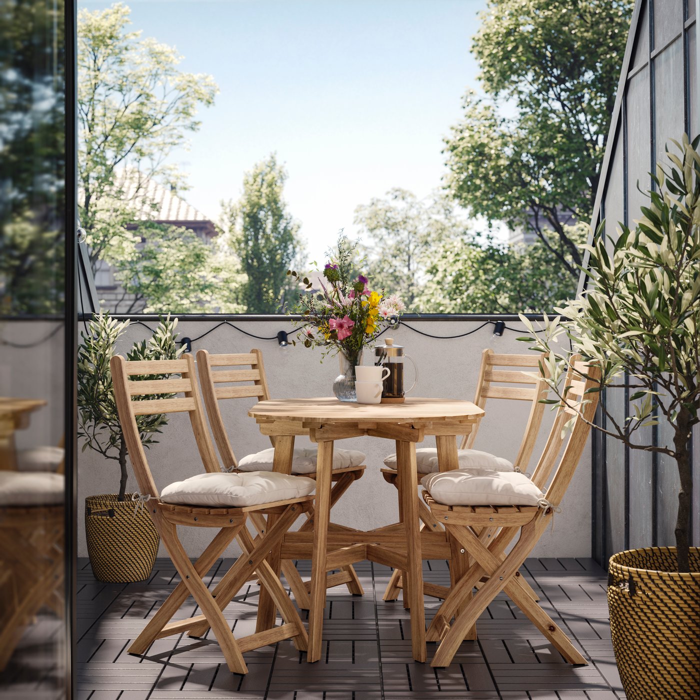 Set da esterno pieghevole ASKHOLMEN in acacia con tavolo rotondo e 4 sedie, completo di cuscini KUDDARNA beige chiaro su un balcone.