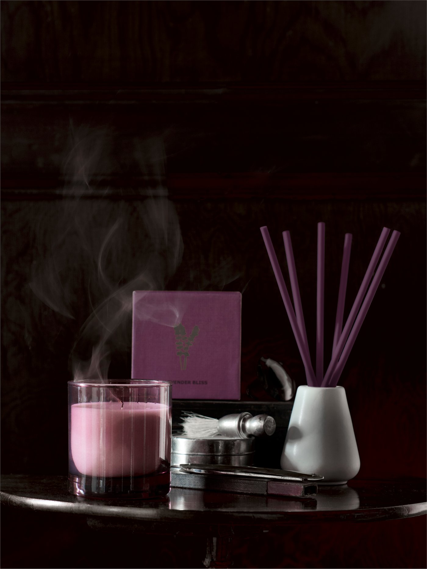 Espelma rosa perfumada SINNLIG i gerro NJUTNING amb barretes perfumades sobre una taula en una habitació fosca.