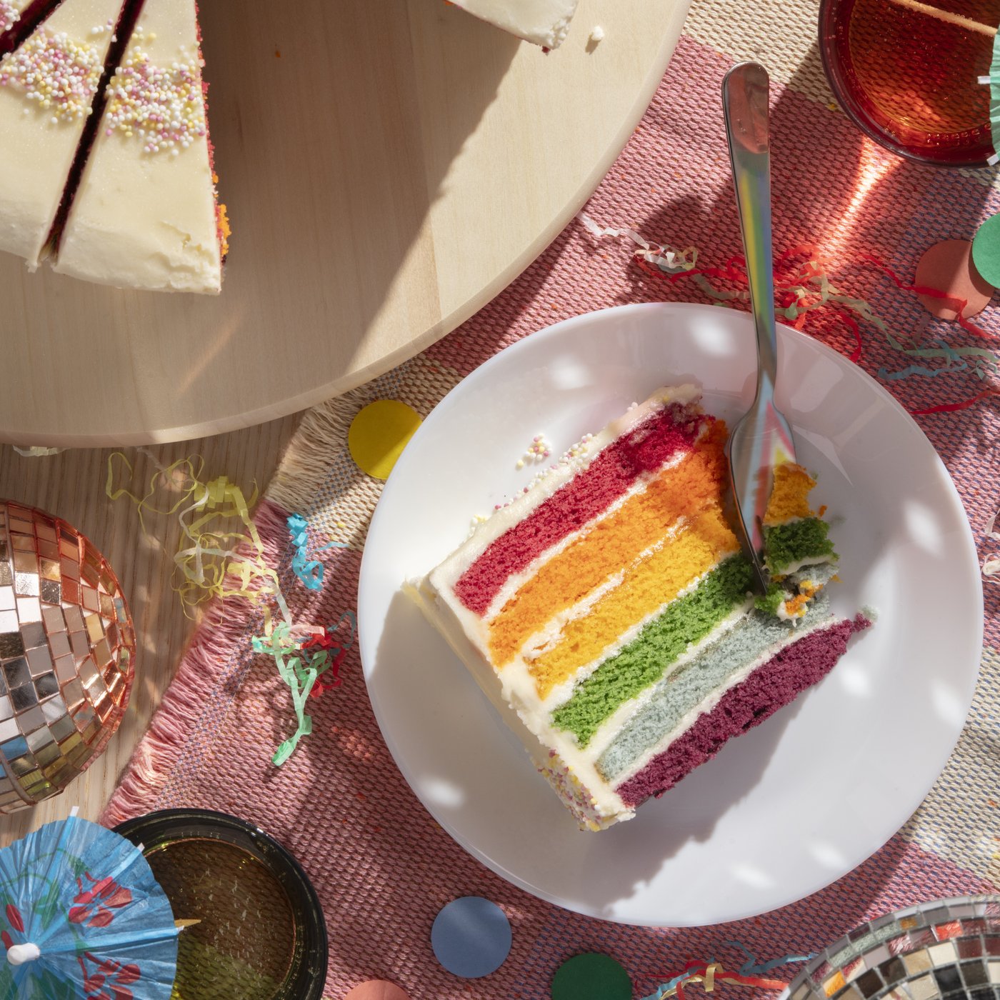 A slice of rainbow cake on a white plate.