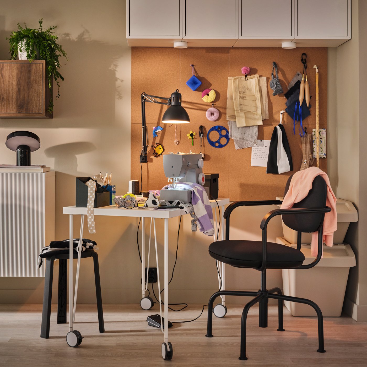 A crafts corner with a white LINNMON-KRILLE desk set up for sewing, next to FLÖNSA memo boards with colourful fabric scraps.