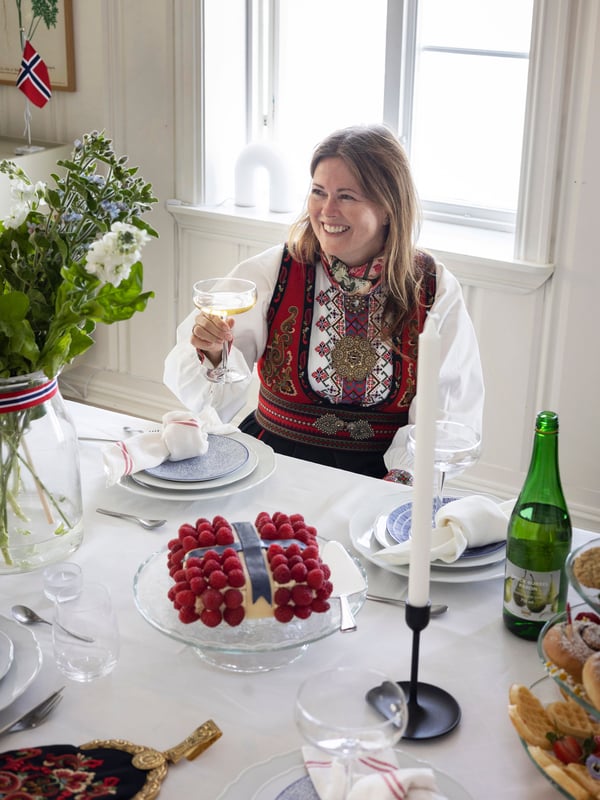 Vertinnen sitter til bords og skåler med sine gjester.