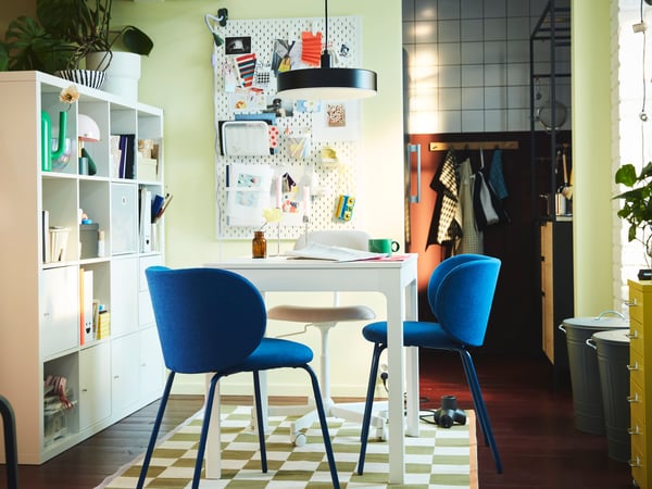 An industrial-style studio home with a dining area consisting of a grey GRÅSALA table and two chairs beside a tiled wall.