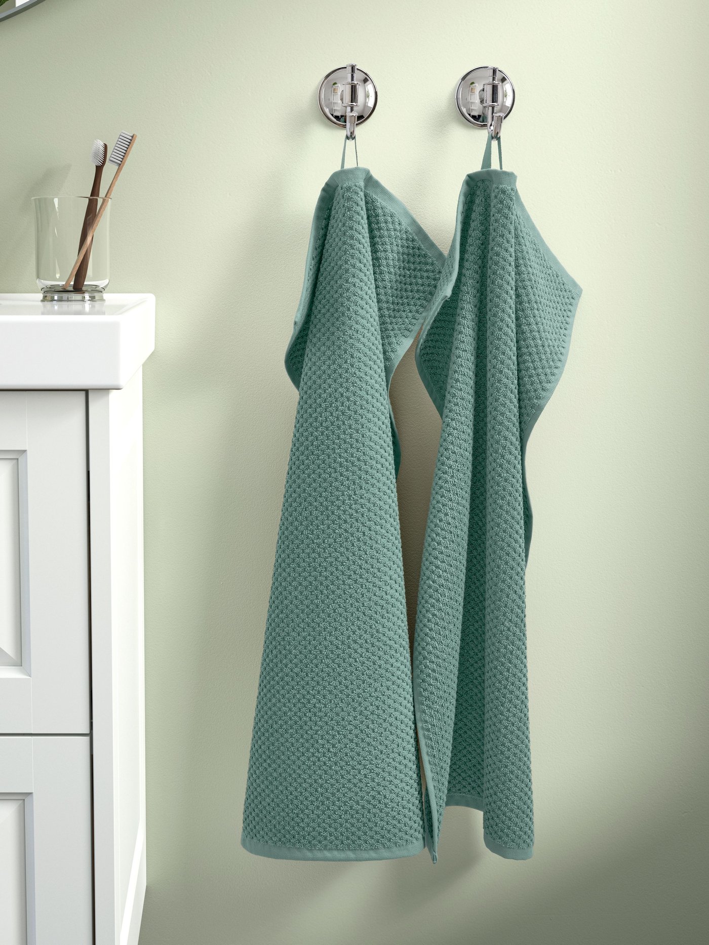 Toallas de mano verde GULVIAL colgadas en la pared.