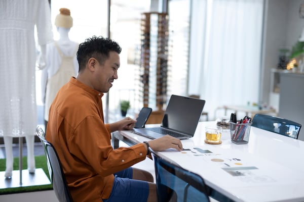 A man sits at his computer in his business.