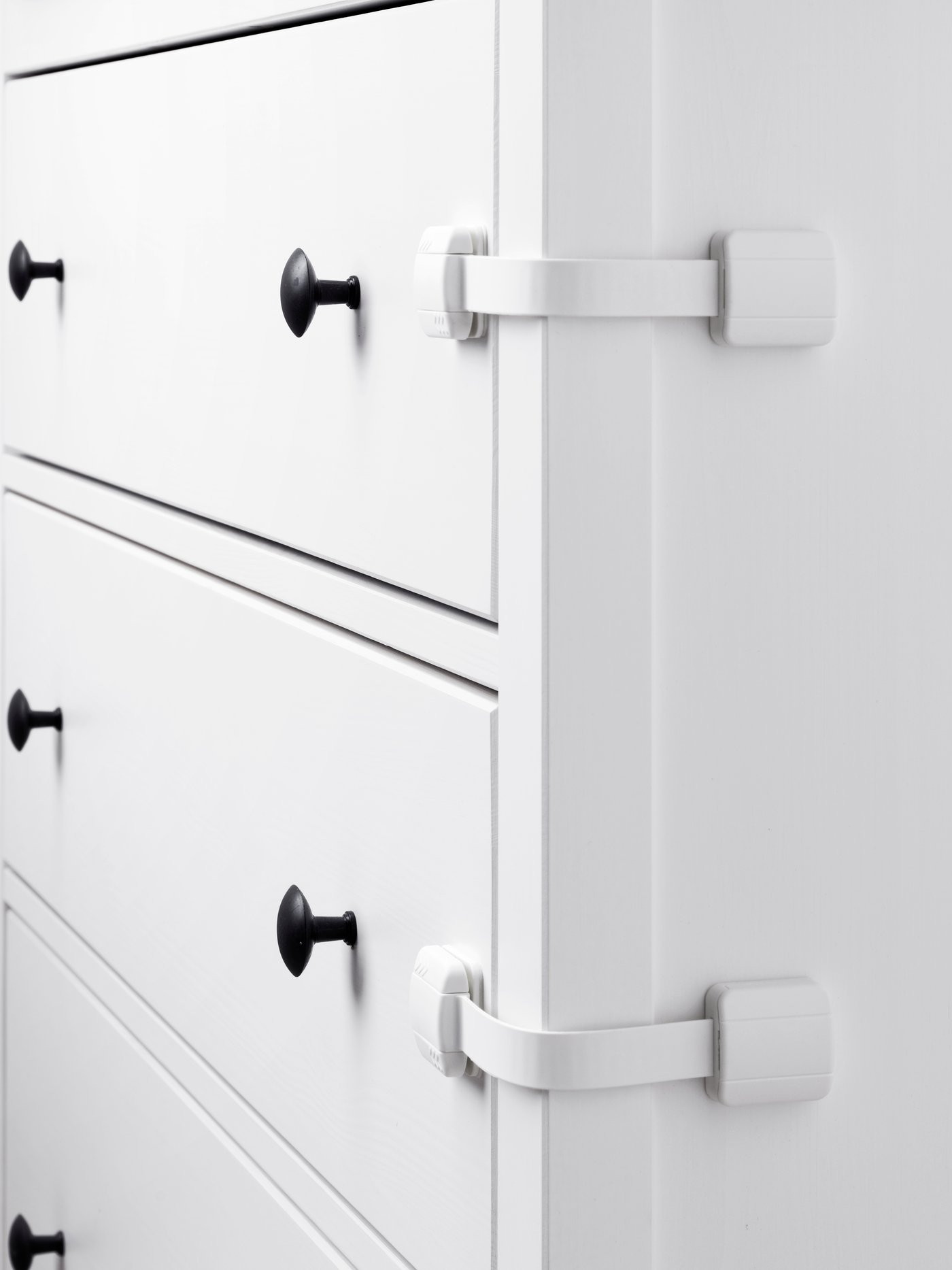 Valkoinen HEMNES-lipasto, jonka laatikoiden sivuun on kiinnitetty UNDVIKA-monitoimisalpa.