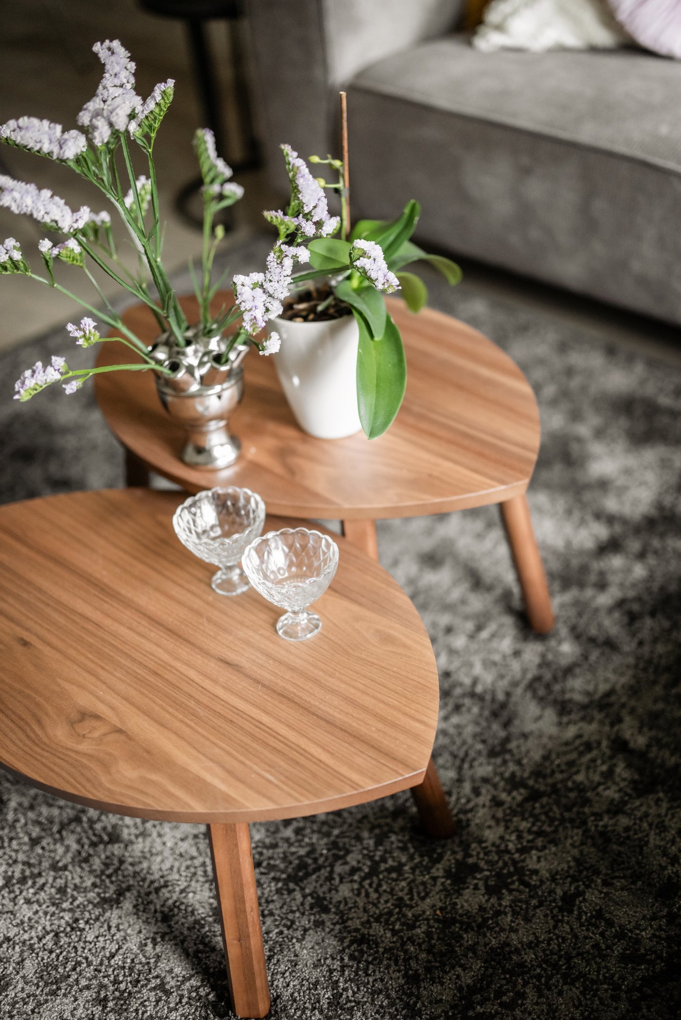 Close-up van twee STOCKHOLM bijzettafeltjes in walnootfineer. Op het ene tafeltje staan twee vazen met bloemen, op de andere staan twee glazen.