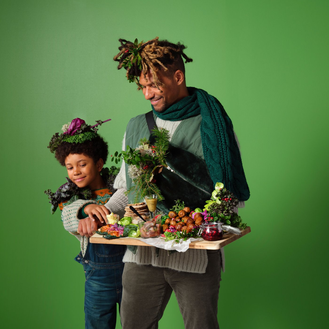 Ein Mann und ein Sohn, die ein Weihnachtsbuffet auf einem Holzbrett in der Hand tragen.