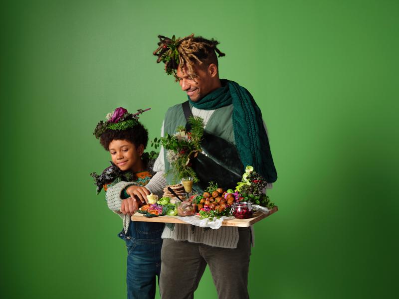 Ein Mann und ein Sohn, die ein Weihnachtsbuffet auf einem Holzbrett in der Hand tragen.