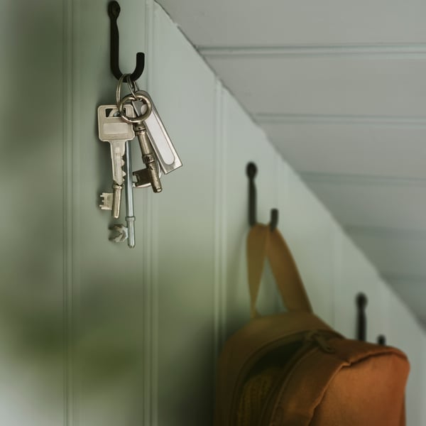 A close up of a dusky muted green wall with HÖGAFFEL hooks shows a bunch of keys hanging from one of the hooks.