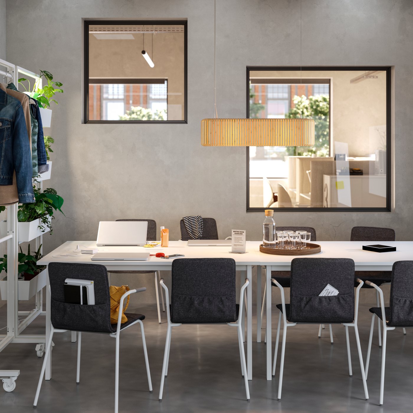 Meeting room with simple, streamlined design, featuring white tables and black upholstered conference chairs.