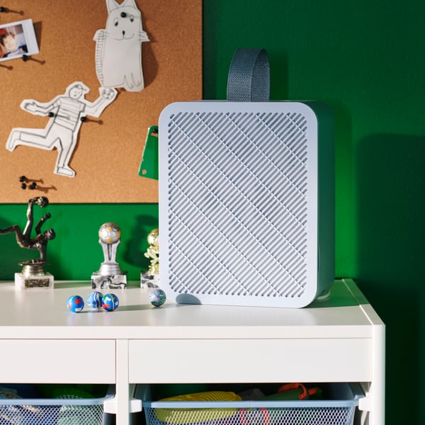 An UPPÅTVIND air purifier in blue, placed on a white desk in a children’s room with green walls and a hand-drawn bunny.