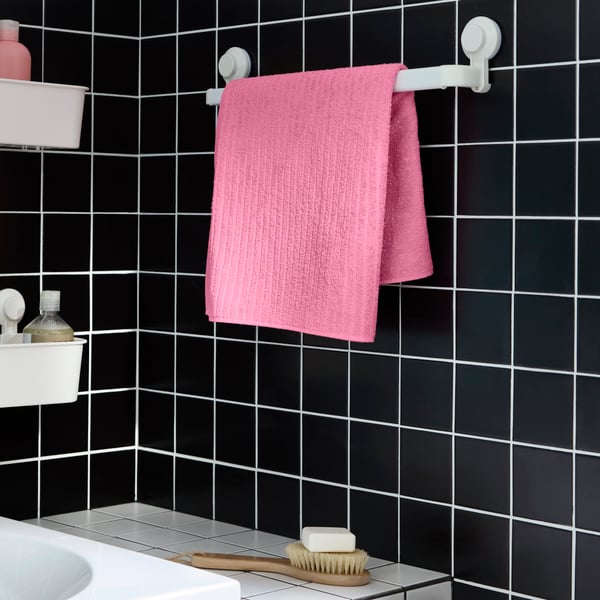 Pink VÅGSJÖN towel draped over a TISKEN towel rail in the bathroom over a bathroom sink.