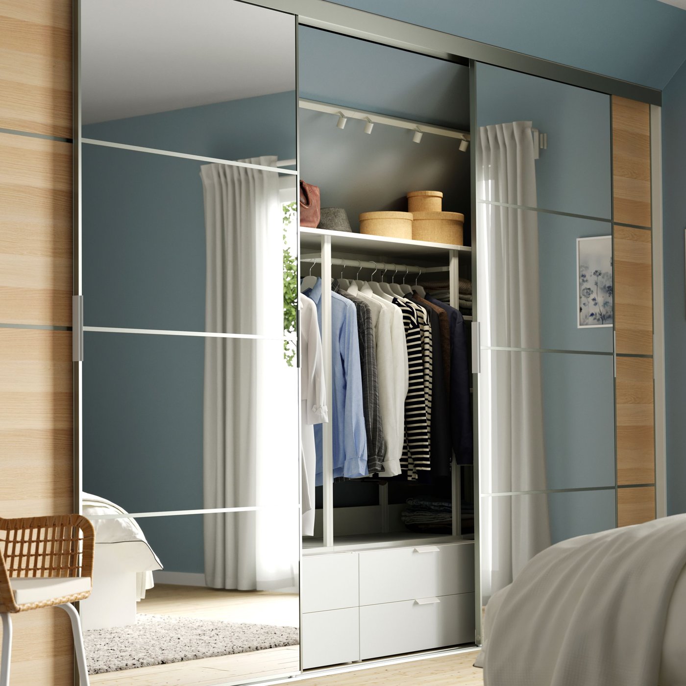 Un sistema di ante scorrevoli SKYTTA in una camera da letto luminosa. Le ante sono parzialmente aperte e lasciano intravedere vestiti e contenitori all'interno.