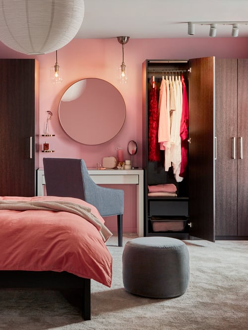 Une chambre à coucher moderne a une coiffeuse MALM blanche comme coin lavabo sous un miroir, entre des armoires avec portes noir-brun.