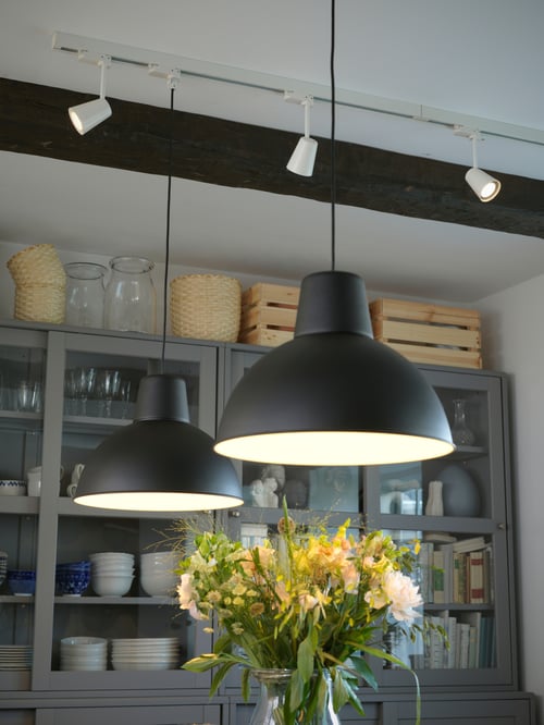 A dining room ceiling that has two black SKURUP pendant lamps with industrial-styled shades by white spotlights on a track.