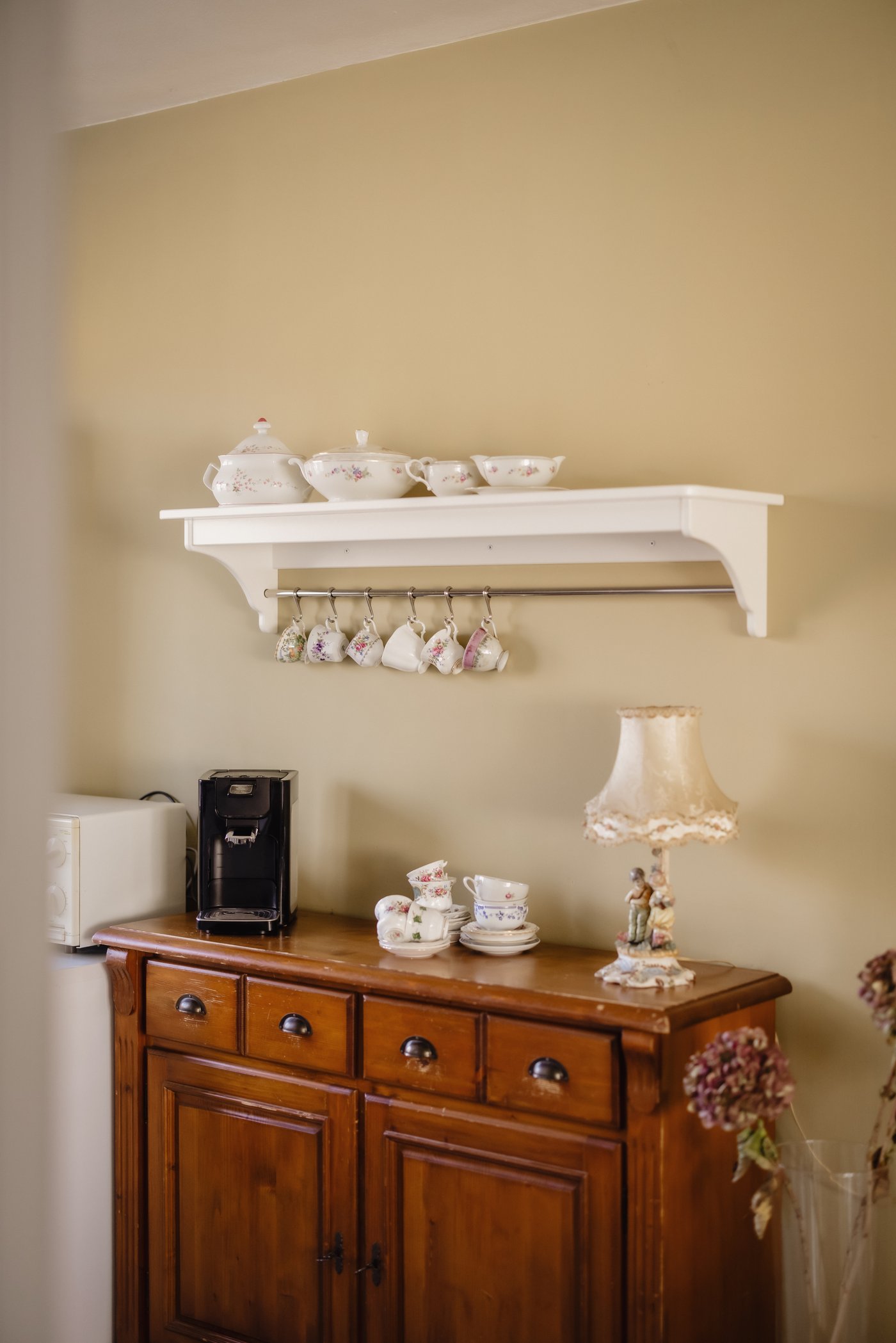 Muur in de keuken met een houten ladekast en daarboven een wandplank.