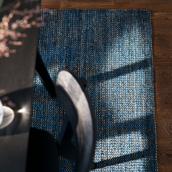 A LANDBANA rug in blue made from natural jute with a LISABO table in black and a LISABO chair in black standing on it.