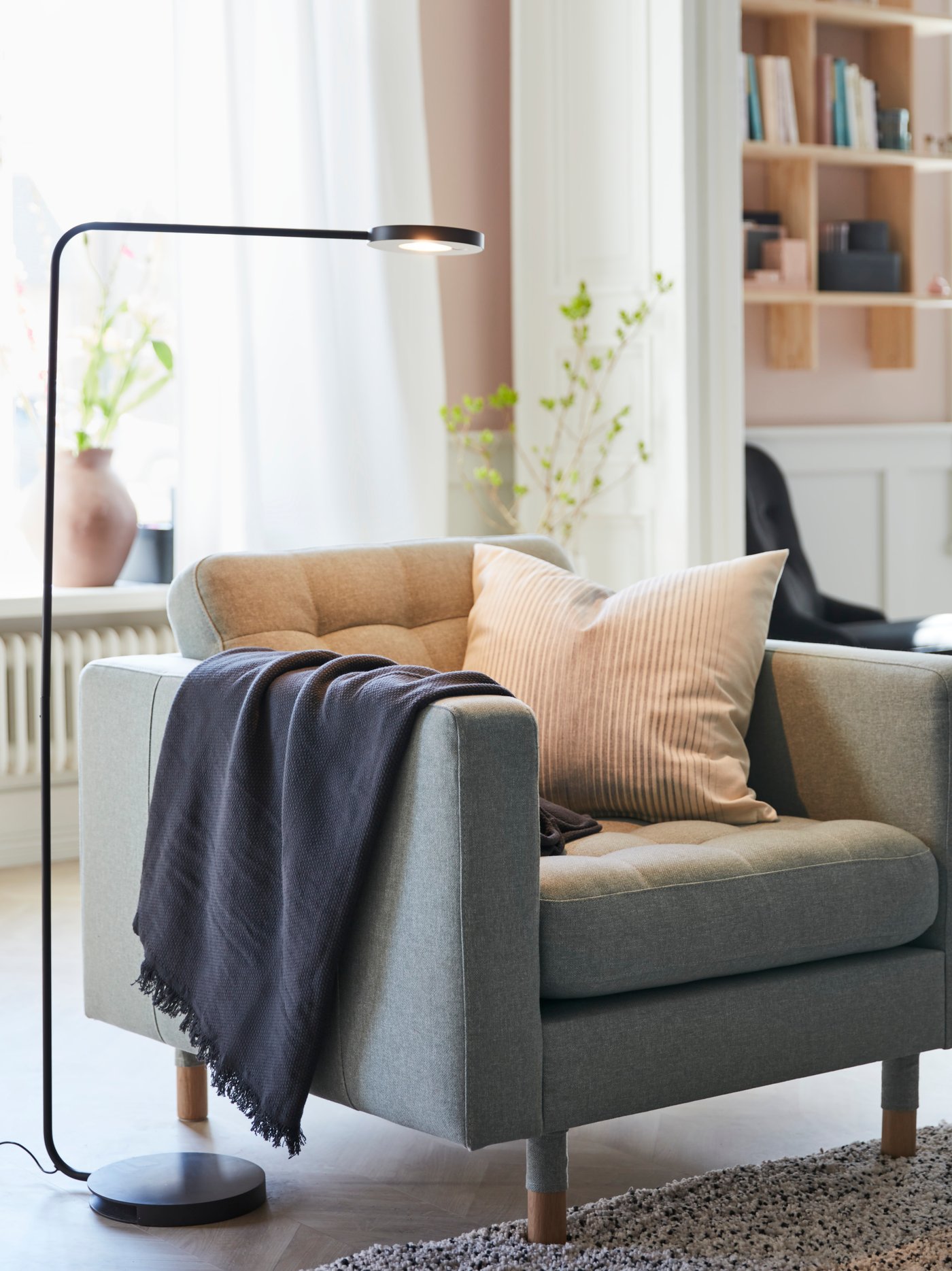 Un sillón LANDSKRONA con mantas y cojines encima en la esquina de una sala.